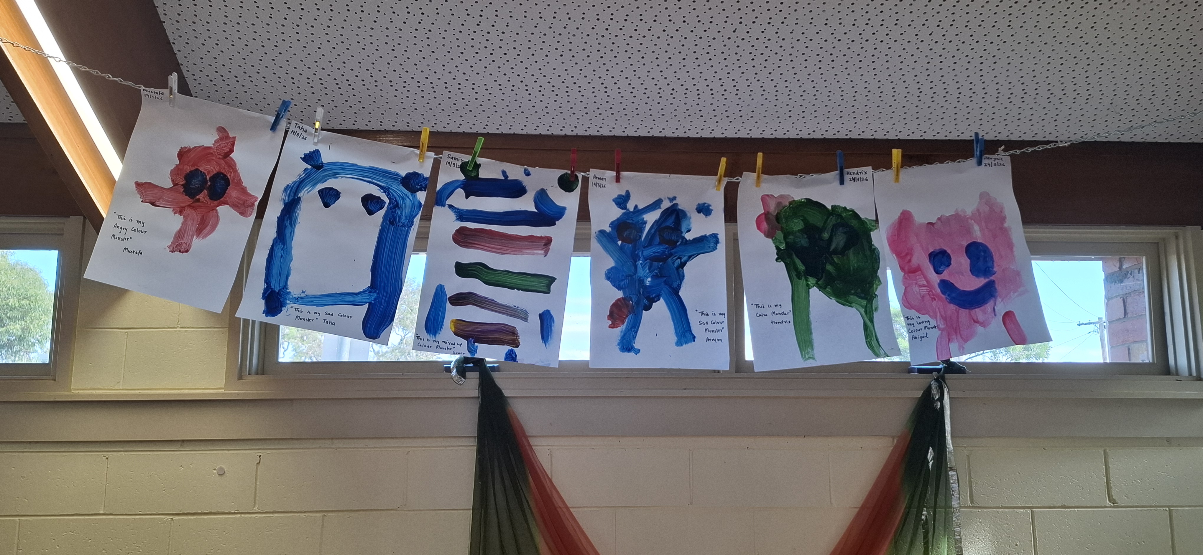 Paintings of colour monsters hanging on a line for display
